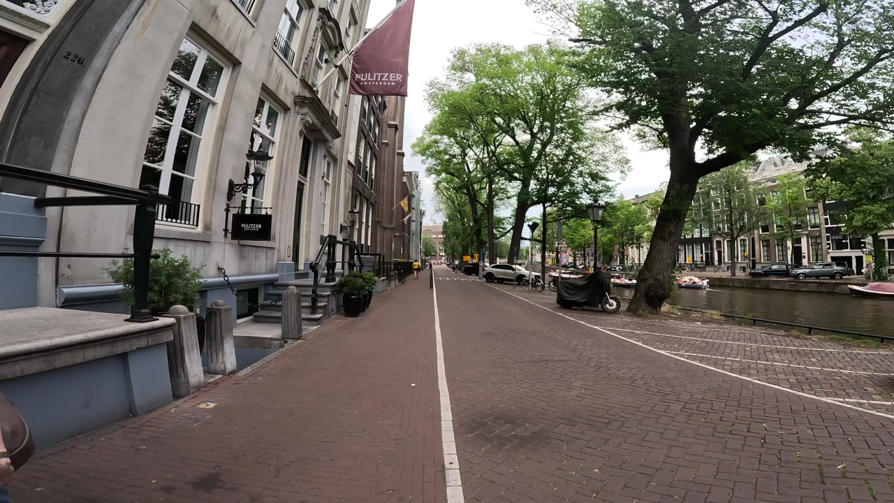 A canal-side brick street in Amsterdam, with the Pulitzer hotel on the left.